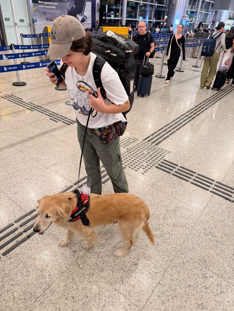 Tutor caminhando com Golden Retriever service dog pelo terminal do aeroporto